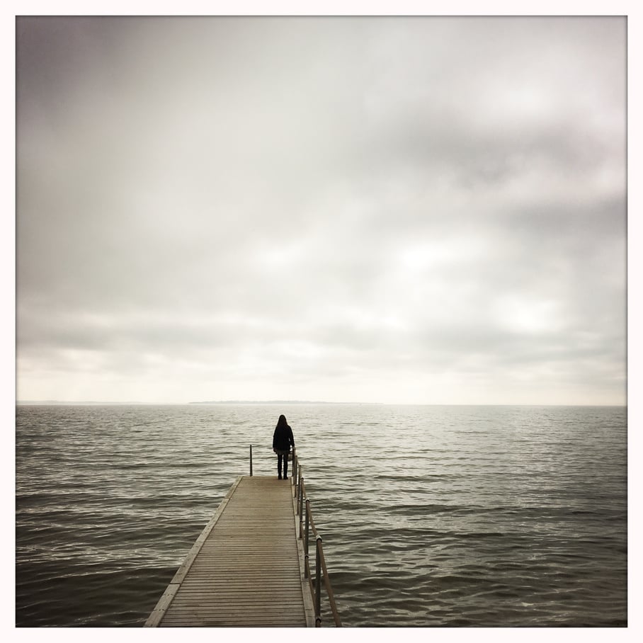 Person standing on a jetty looking towards the sea