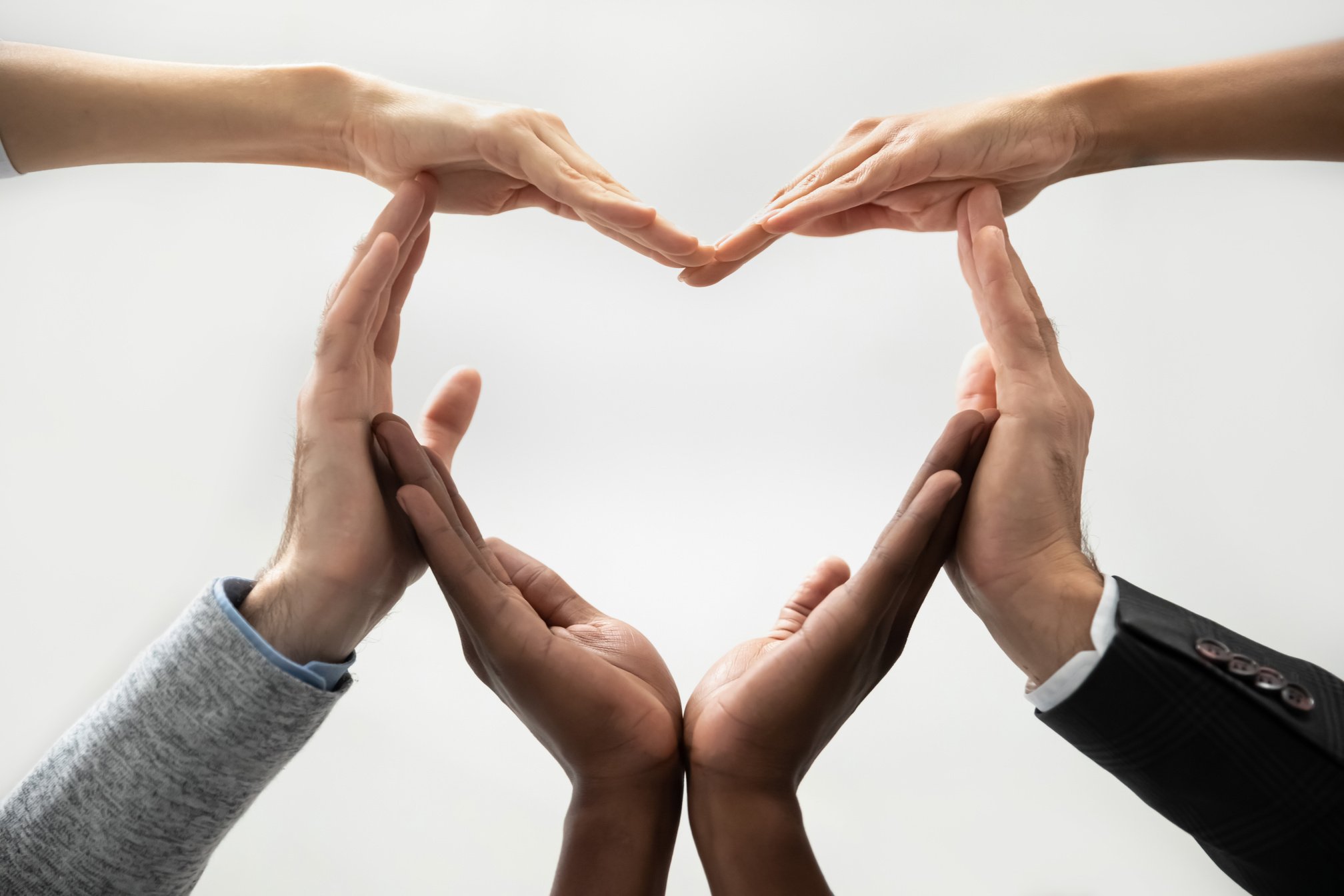 Concept of diverse business people join hands forming heart.